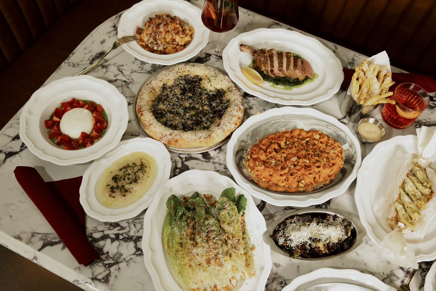 A table laid with lamb chops, burrata, scallop crudo, vodka rigatoni and wood-fired pizza